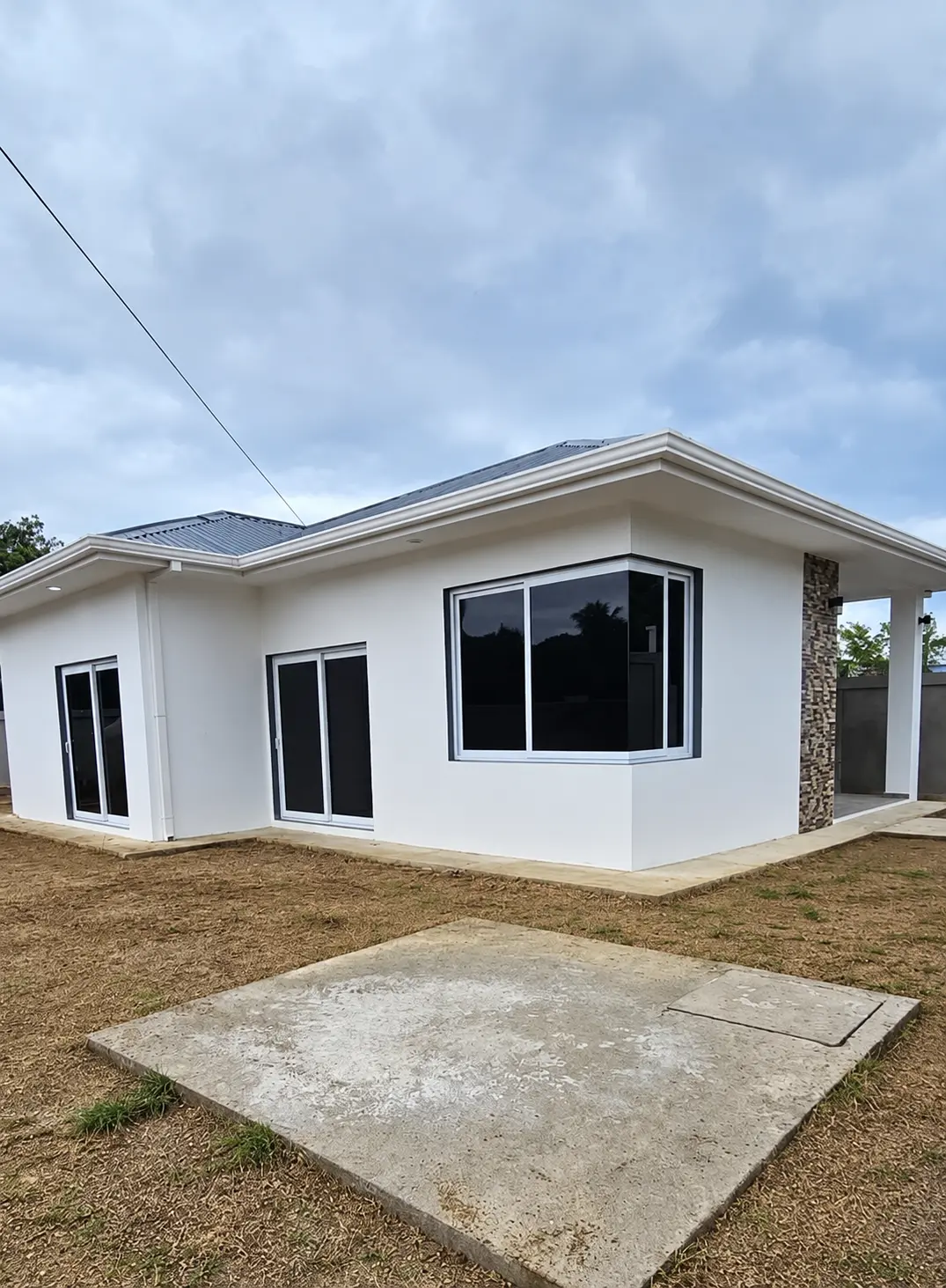 Casa blanca con ventanal en esquina, perfiles blancos y vidrio oscuro instalados por ALUR