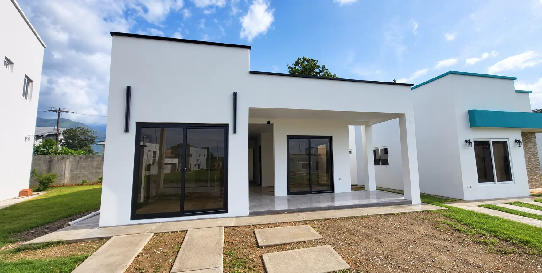 Fachada de casa blanca con grandes ventanas de perfiles negros y vidrio oscuro, instalación de ALUR