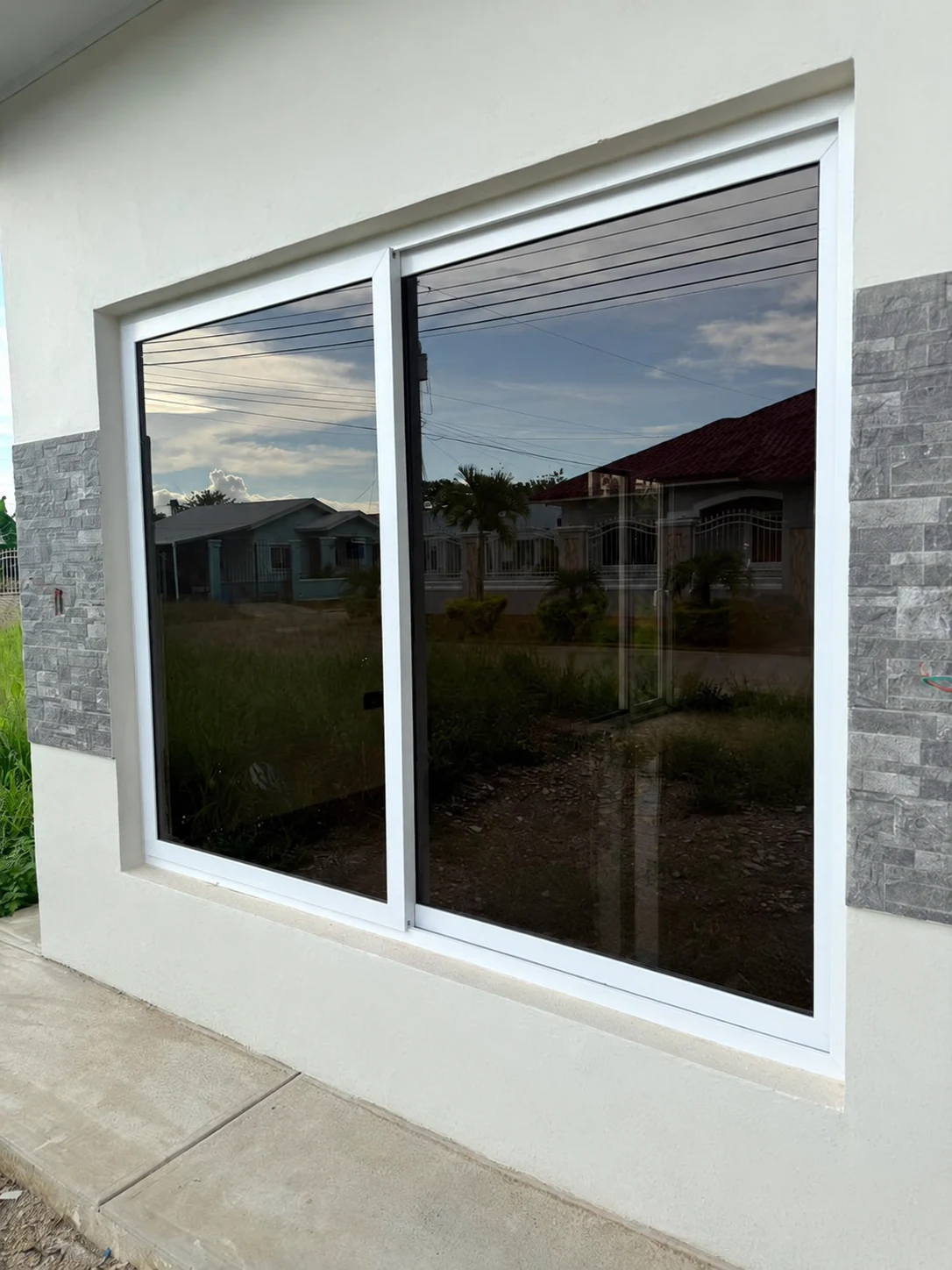 Ventana corrediza de dos hojas con marco blanco y vidrio oscuro instalada por ALUR